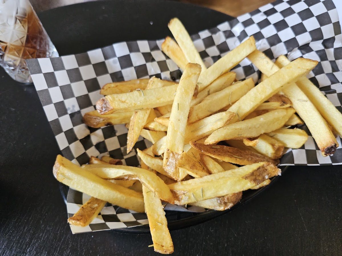 Skin-on fries on black-and-white checked paper.